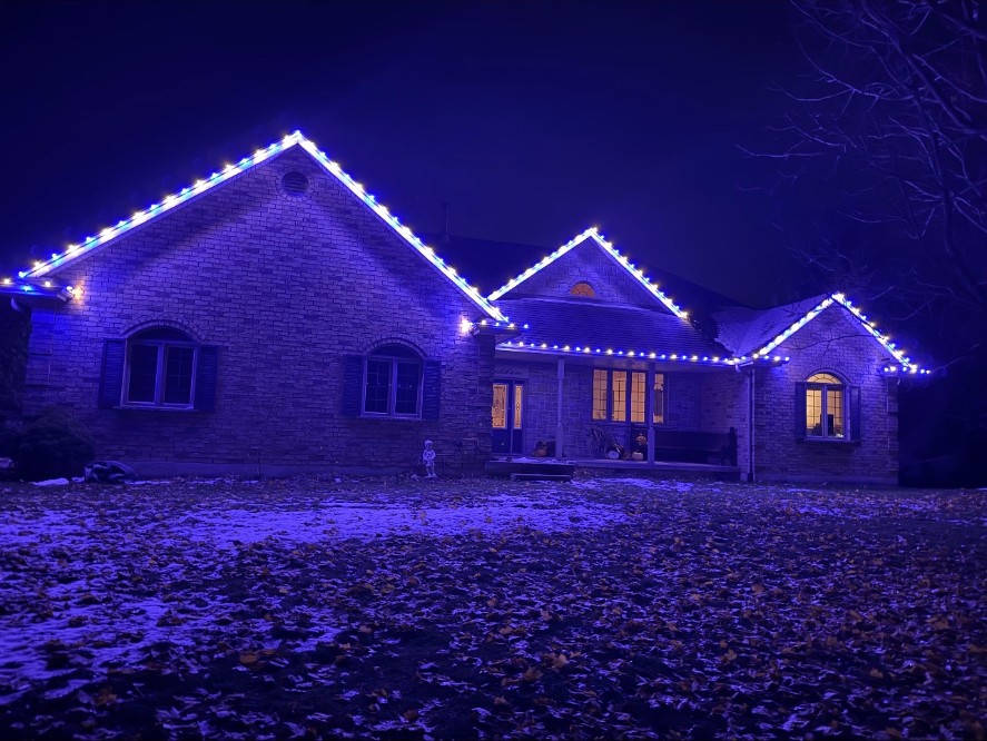 Home outlined in cool blue holiday lights at night